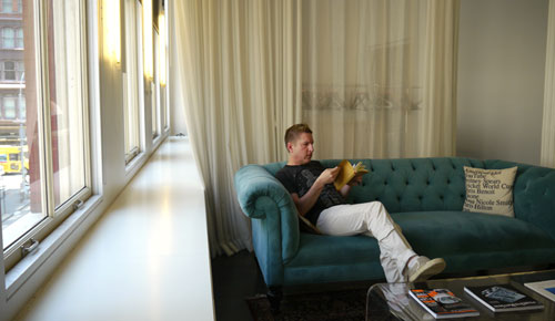 A Man Sitting While Reading in a Sofa on a Living Area