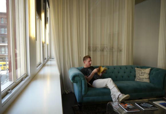 A Man Sitting While Reading in a Sofa on A Living Area