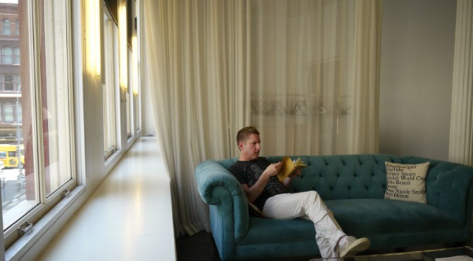 A Man Sitting While Reading in a Sofa on A Living Area